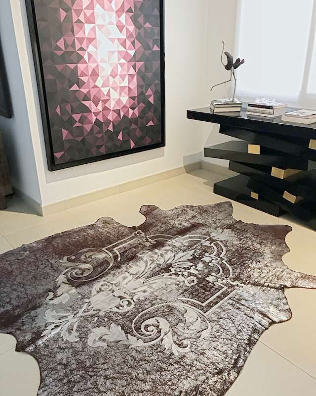 A printed hide with a baroque pattern under a stacked black lacquer console, a geometric work in pinks above