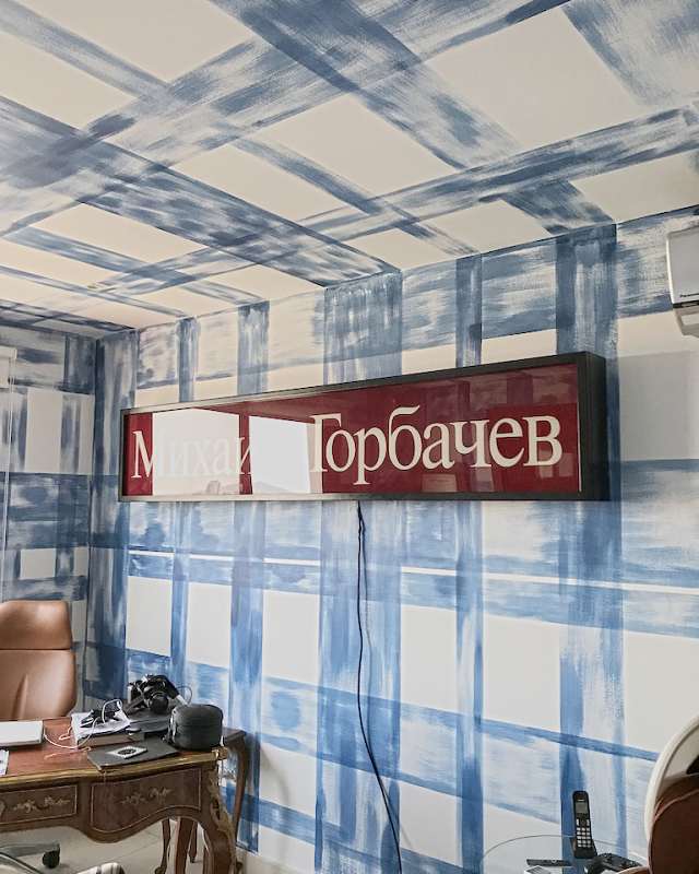 A study with blue brushstrokes painted across walls and ceiling like a check, a long red sign and an antique desk