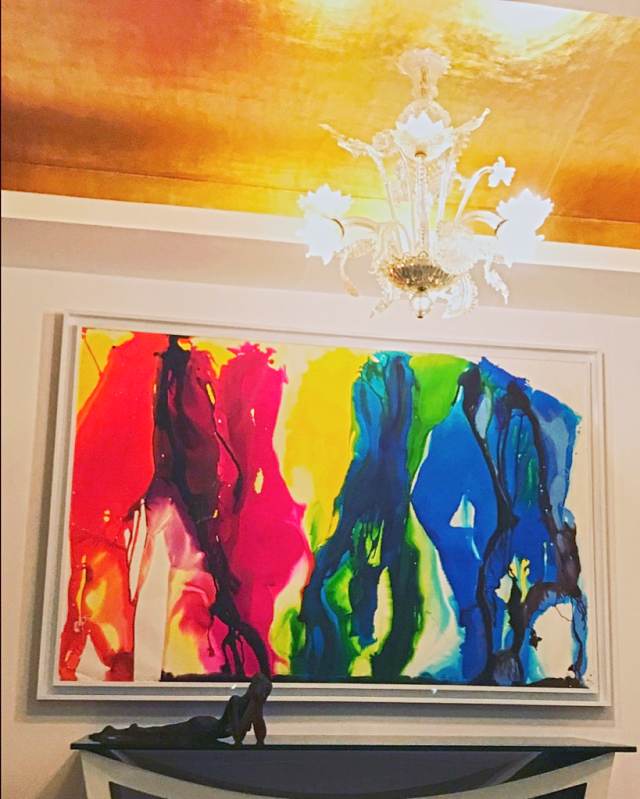 A gold-leaf ceiling with a Murano chandelier over a large colourful abstract work