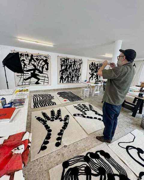 Black and white felt works laid on the floor and pinned to the walls of the artist's studio