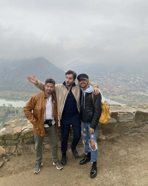 Three men, among them the artist Levan Songulashvili, on a stone lookout above Mtskheta in mist