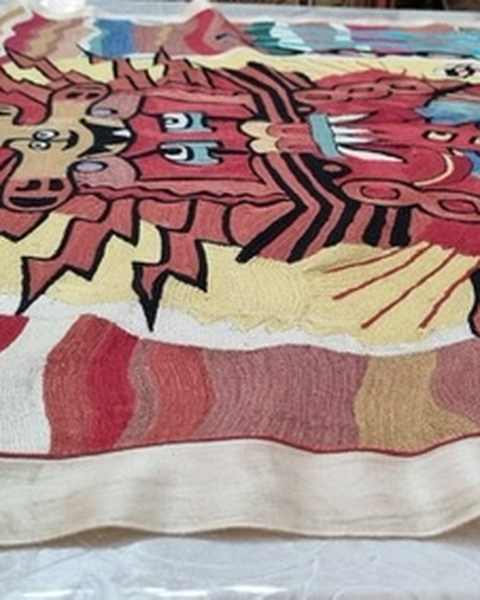 A silk embroidered tapestry with a red face of rays and a wavy striped border, laid on a table