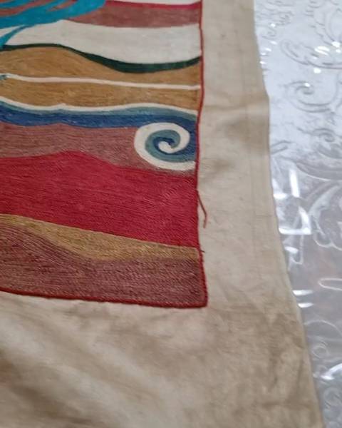 Close-up of silk chain-stitch embroidery in red, ochre, blue and a spiral