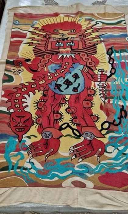 The full tapestry: a red deity with chains, teeth and claws over a blue river, embroidered in silk