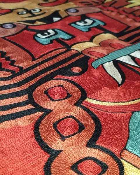 Close-up of the deity’s face and coiled chain in red, black and ochre silk chain stitch