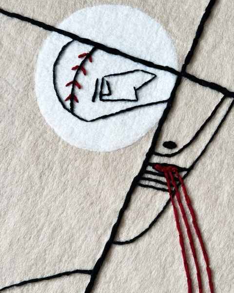 Close-up of black and red wool lines stitched over a white felt circle