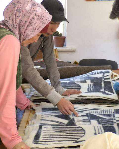 Felt-makers and Vargas-Suárez Universal reviewing a black and white felt panel together
