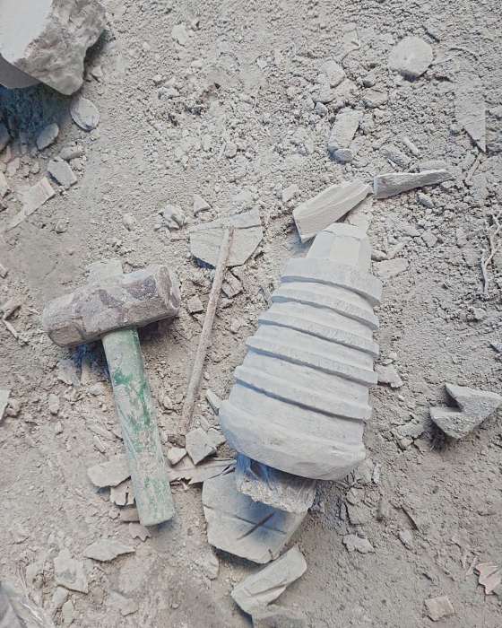 The ringed column lying on stone dust beside a sledgehammer and a chisel