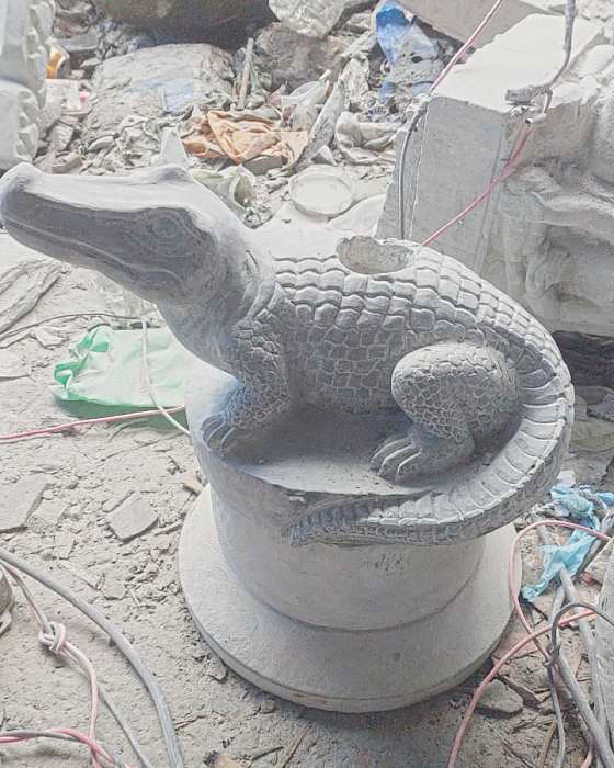 The finished crocodile curled on its round base in the workshop