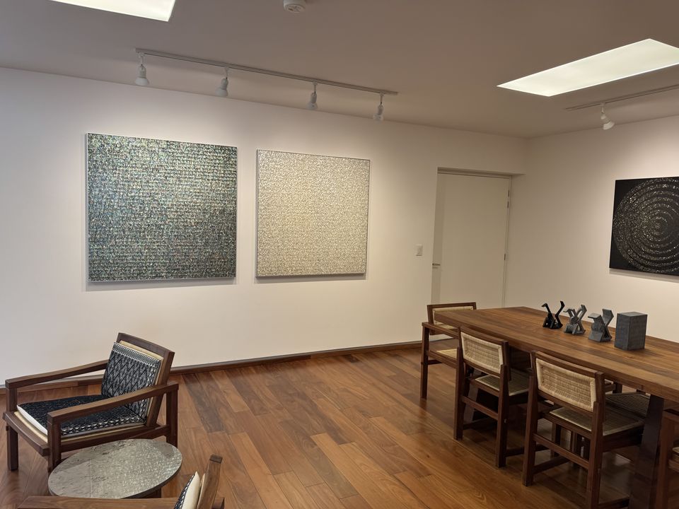 Two square works by Gabriel de la Mora, one in abalone and one in mother of pearl, hanging side by side in a gallery room