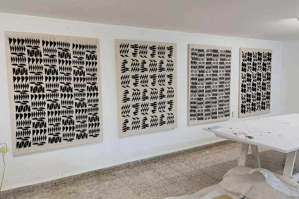 Four bogolan panels in black on natural cotton hanging in a white studio