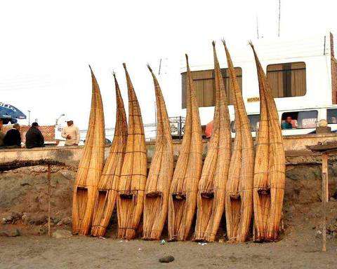 Reed boats made of bundled totora standing upright against a sea wall