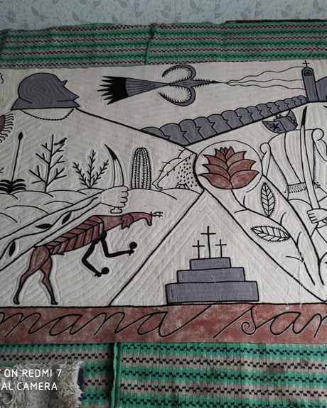 A long white felt with black drawings of figures, a church and crosses, titled Semana Santa