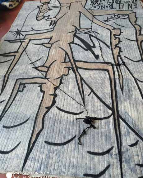 A grey-blue felt with a figure drawn in black on a tree trunk