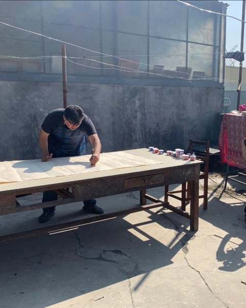Vargas-Suárez Universal working over a long sheet of paper on a rooftop table, filmed by two cameras