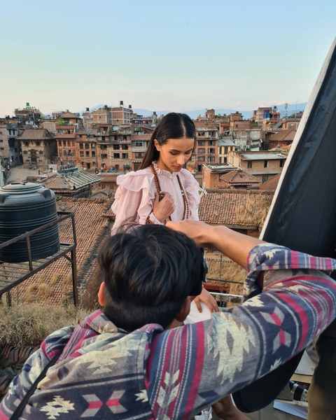 A photographer framing a model on a Bhaktapur rooftop at dusk