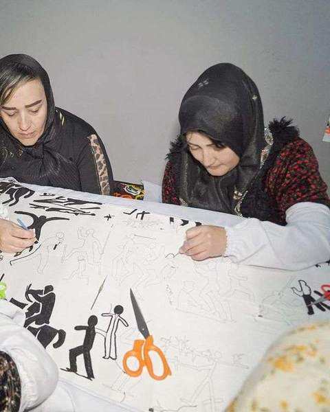 Two embroiderers working side by side on the black figures of the suzani