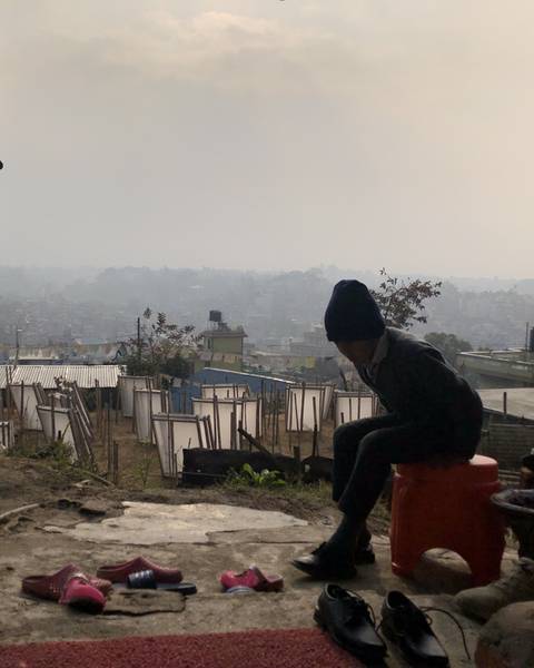 A figure in silhouette looking out over paper moulds drying on a hillside