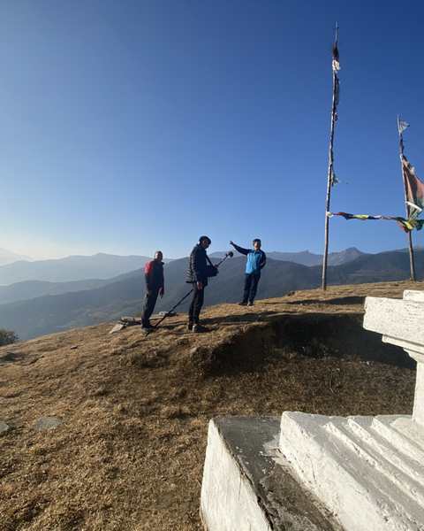 An interview on a hilltop beside a white stupa, a boom microphone held out, mountains behind
