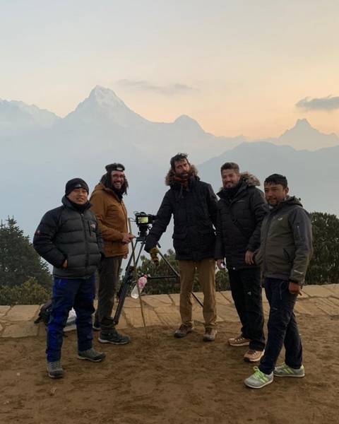 The film crew with a camera on a tripod at dawn, the Annapurna range behind
