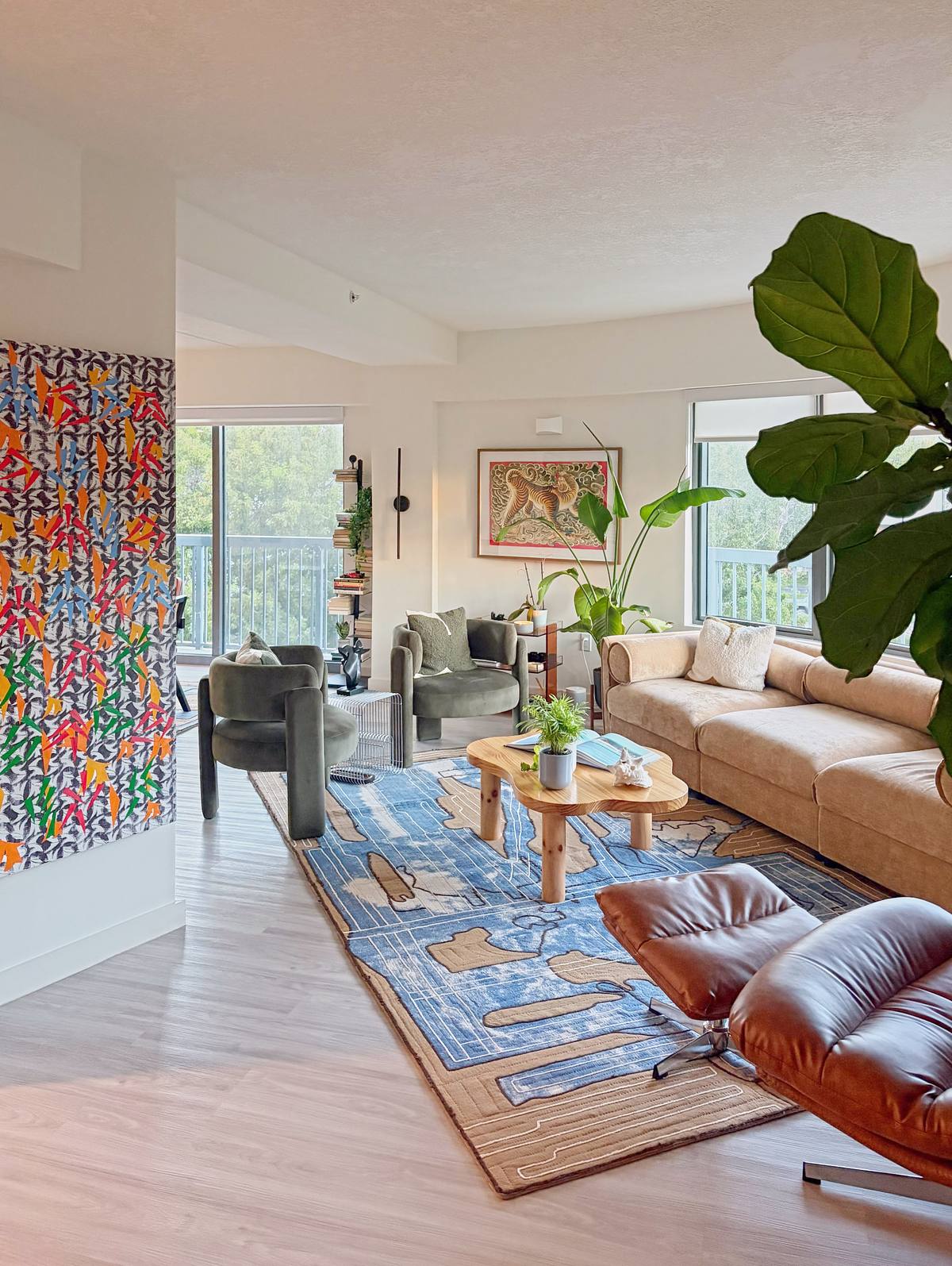 Open living room: a patterned blue rug, a cognac leather lounge chair and a pine coffee table