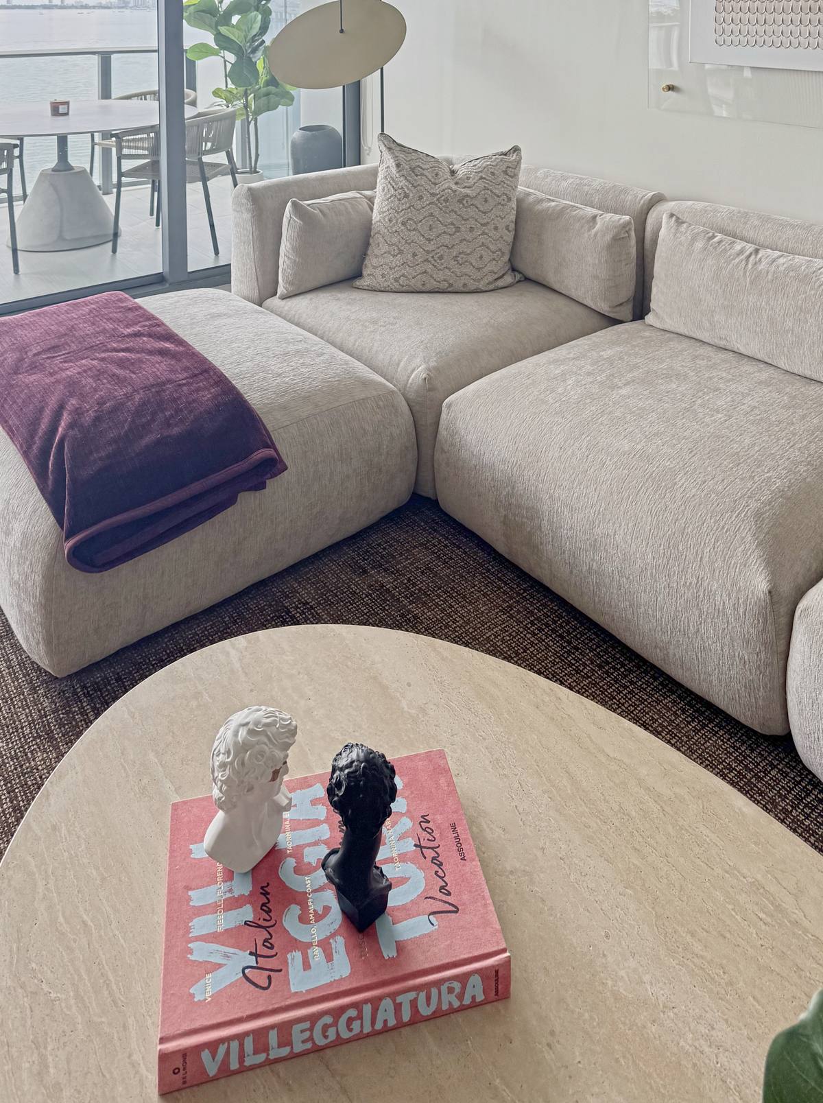 The sectional and an oval travertine coffee table